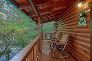A wooden cabin with a porch featuring rocking chairs and a view of the surrounding forest. - April's Diamond Cabin Rental (Wears Valley)