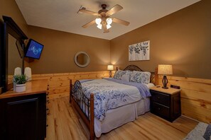 A bedroom with a bed, bedside lamps, a ceiling fan, a TV, and a clock. - Autumn Breeze | Hot Tub | Pool Table | Fireplace (Pigeon Forge)