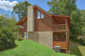 Eine Blockhütte mit einem Steinkamin, einem Balkon und einer Klimaanlage.