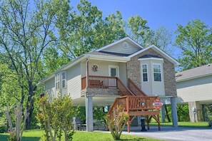 A two-story house with a stone foundation, a covered porch, and a staircase leading to the upper level. - Bear Paw Chalet Cabin Rental (Pigeon Forge)