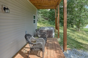 Une terrasse en bois avec deux fauteuils en osier et un jacuzzi.