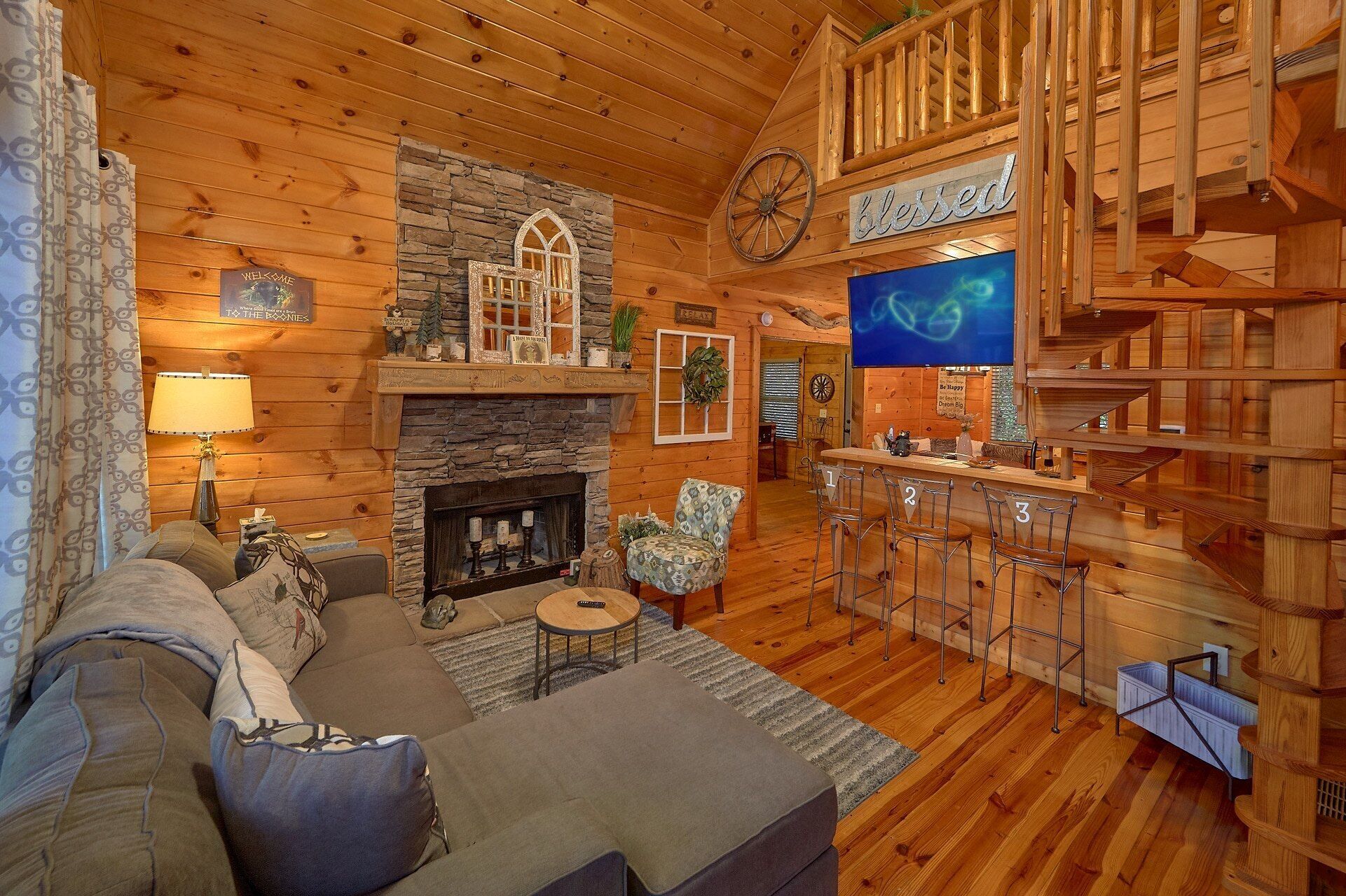A cozy log cabin interior with a fireplace, a bar area, and a comfortable seating arrangement.