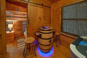 A wooden interior with a barrel-shaped bar stool, a window with blinds, and a 'Welcome' sign. - Bears Hideaway Cabin Rental (Sevierville)