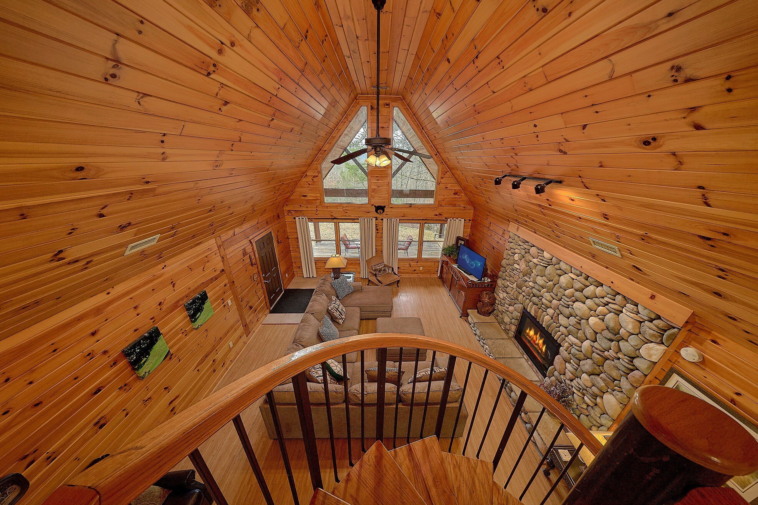 A wooden interior with a spiral staircase, a stone fireplace, and a television.