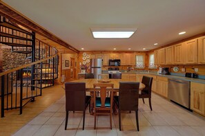 A spacious kitchen with wooden cabinets, a central island, and a stone fireplace. - Big Bear Cabin Rental (Pigeon Forge)