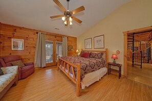 A wooden-paneled bedroom with a bed, a chair, a nightstand, and a ceiling fan. - Big Bear Cabin Rental (Pigeon Forge)