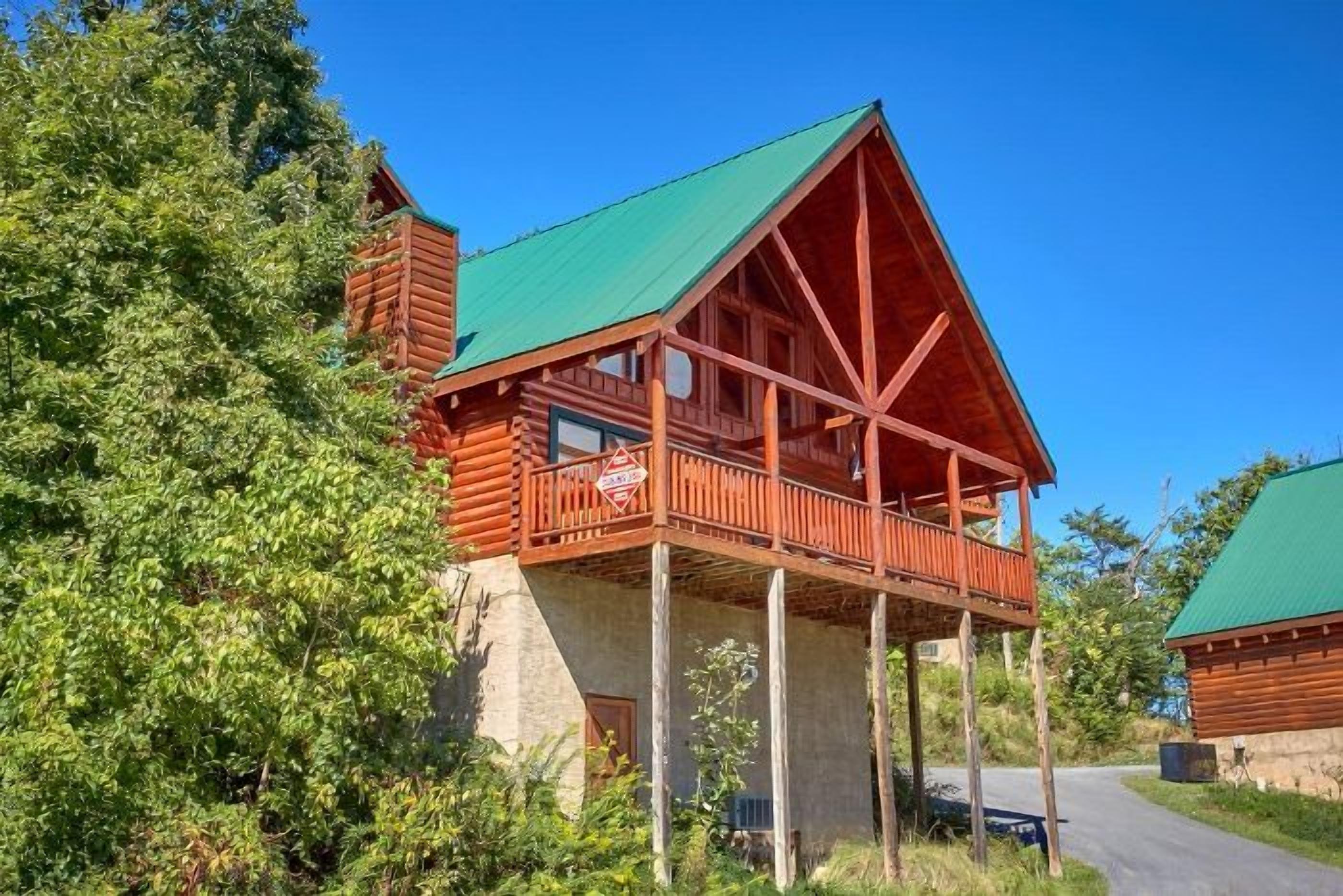 A wooden cabin with a balcony, surrounded by trees.