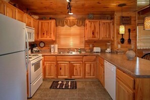 A kitchen with wooden cabinets, a refrigerator, stove, and a dishwasher. - Catch of the Day | Mtn Views, Hot Tub, Game Room, Pigeon Forge, Fireplace + Free Attraction Tickets (Pigeon Forge)