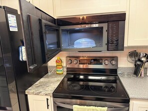 Una cocina con un refrigerador negro, un microondas y una estufa LG.