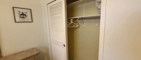 Un armario con espacio para colgar y una puerta de paneles listones.