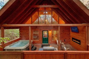 A log cabin with a hot tub, a fireplace, and a bench outside. - Lion's Den | Hot Tub, Game Room, Sauna, Pigeon Forge, Fireplace + Free Attraction Tickets (Pigeon Forge)