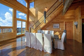 A spacious room with a wooden interior, a dining table set for six, and a staircase leading to an upper level. - Copper Ridge Lodge | Private Pool, Dollywood Views, Game Room, Sleeps 12 + Free Attraction Tickets (Sevierville)