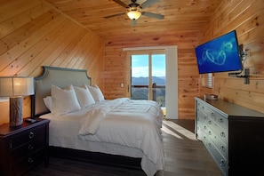Ein Schlafzimmer mit Holzwänden, einem Bett, einer Kommode und einem Fernseher.