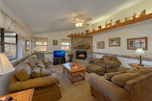 A living room with a fireplace, a television, and multiple sofas. - Creekside Cottage | Hot Tub, Fire Pit, Fireplace + Free Attraction Tickets (Wears Valley)