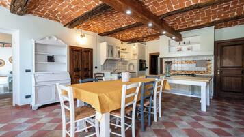 Une cuisine rustique avec un plafond en briques apparentes, des meubles blancs et un sol carrelé.