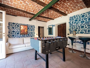 A room with a foosball table, a sofa, and a brick wall with a blue pattern.