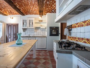 A kitchen with a brick ceiling, white cabinets, a wooden table, and a gas stove.
