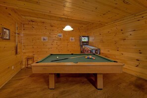 A pool table in a room with wooden walls and a ceiling. There is a television mounted on the wall. - Cuddly Critters | Hot Tub, Game Room, Sleeps 12, Pigeon Forge, Fireplace + Free Attraction Tickets (Pigeon Forge)