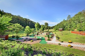 Ein Golfplatz mit mehreren Grüns und einem roten Gebäude im Hintergrund.