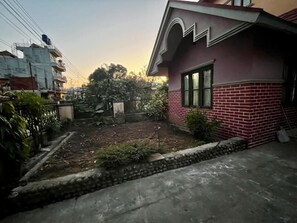 A residential area with a house featuring a brick facade and a small garden.