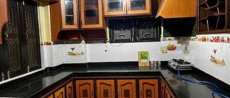 A kitchen with wooden cabinets, a black countertop, and a patterned floor.
