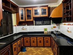 A kitchen with wooden cabinets, a black countertop, and a patterned floor.