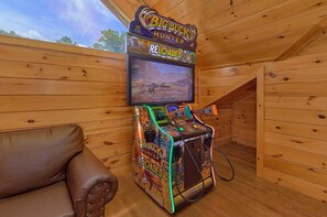 Ein Zimmer mit Holzboden, einer fest installierten Videospielkonsole und einem Fernseher, der ein Spiel zeigt.