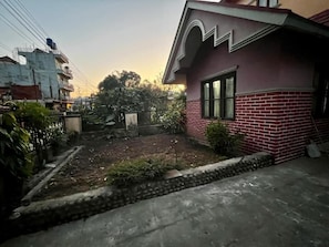 A residential area with a house featuring a brick facade and a small garden.