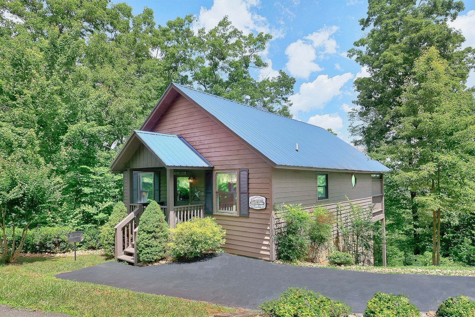A small cabin with a porch, surrounded by trees.