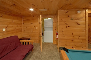 A wooden cabin interior with a sofa, a pool table, and a refrigerator. - Jasmine's Retreat | Hot Tub, Game Room, Fireplace + Free Attraction Tickets (Wears Valley)