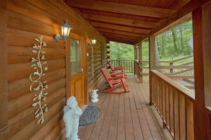 A wooden cabin with a porch, rocking chairs, and decorative angel statues. - Jasmine's Retreat | Hot Tub, Game Room, Fireplace + Free Attraction Tickets (Wears Valley)