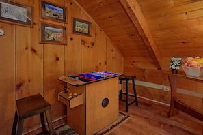 A wooden room with a sloped ceiling, a small bar area with a digital screen, and a wall-mounted thermostat. - Just Barely Making It | Hot Tub, Fireplace + Free Attraction Tickets (Wears Valley)