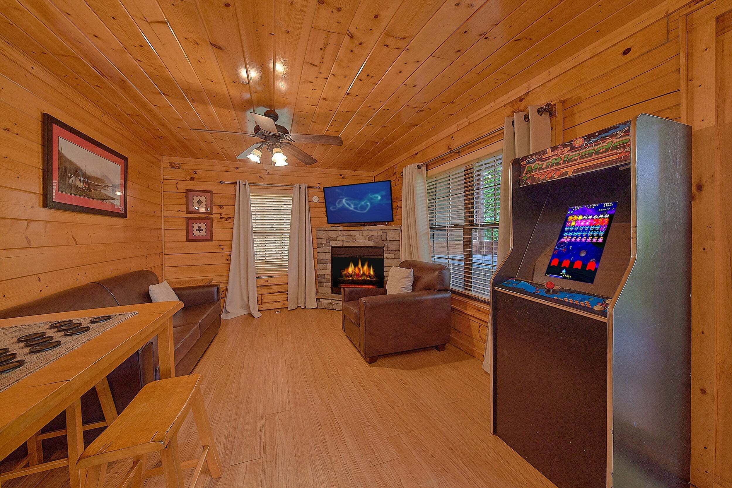 Interior acogedor de una cabaña con paredes de madera, chimenea, televisor y consola de videojuegos.