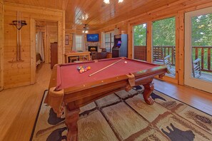 Ein Holzinterieur mit einem Billardtisch, einem Fernseher und einem Kamin.