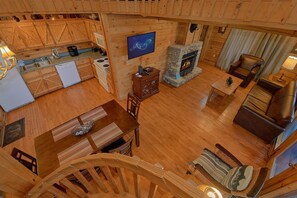 Amplia sala de estar con chimenea, muebles de madera y una cocina equipada con electrodomésticos modernos.