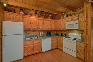 Eine Küche mit Holzschränken, einem Kühlschrank, einer Mikrowelle, einem Herd und verschiedenen Küchengeräten.