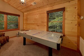 A room with a foosball table, wooden walls, and large windows. - Little Wren | Hot Tub, Game Room, Gatlinburg, Fireplace + Free Attraction Tickets (Gatlinburg)
