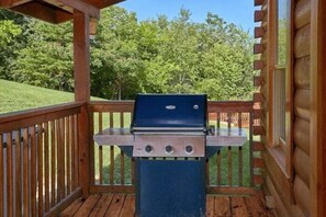 A barbecue grill on a wooden deck with a view of a green landscape. - Lookin Up | Hot Tub, Game Room, Pigeon Forge, Resort Pool, Fireplace + Free Attraction Tickets (Pigeon Forge)