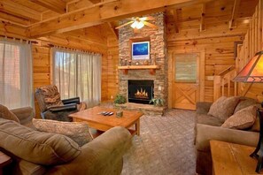 A cozy log cabin interior with a fireplace, wooden furniture, and a stone accent wall. - Lookin Up | Hot Tub, Game Room, Pigeon Forge, Resort Pool, Fireplace + Free Attraction Tickets (Pigeon Forge)