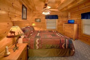 A wooden cabin bedroom with a bed, dresser, lamp, and ceiling fan. - Lookin Up | Hot Tub, Game Room, Pigeon Forge, Resort Pool, Fireplace + Free Attraction Tickets (Pigeon Forge)