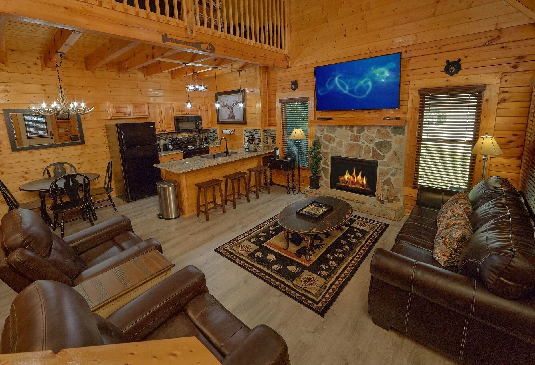 A log cabin interior with a bar, seating area, fireplace, and a television.