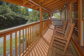 A wooden deck with a railing, a table, and two chairs. - Lovers Paradise | Hot Tub, Game Room, Pigeon Forge, Resort Pool, Fireplace + Free Attraction Tickets (Pigeon Forge)