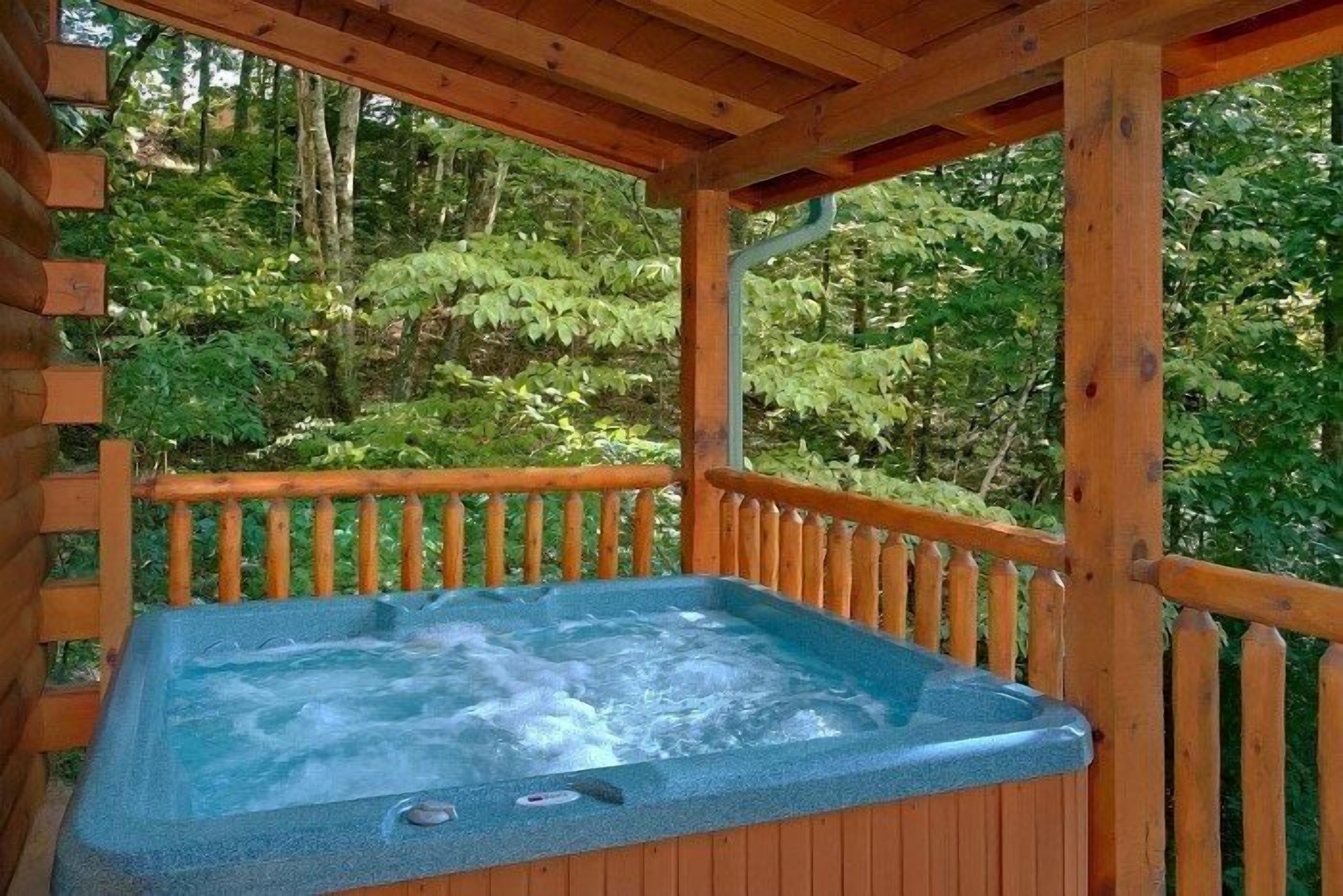 A hot tub in a wooden gazebo with a view of a forested area.