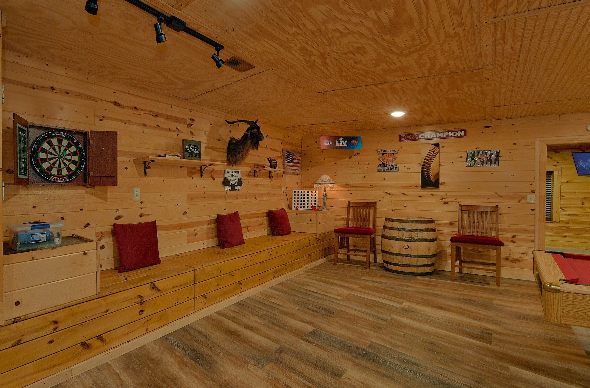 Ein Holzraum mit Dartscheibe, einer Willkommensschild und einem Schild, das einen Bereich für Live-Spiele kennzeichnet.