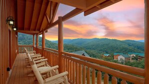 A wooden deck with a view of a forested mountain range.