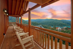A wooden deck with a view of a forested mountain range.