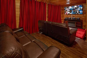 A home theater with leather seating, a television, and a wooden cabinet with snacks. - Major Oaks | Theater, Hot Tub, Game Room, Sleeps 12, King Suites + Free Attraction Tickets (Pigeon Forge)