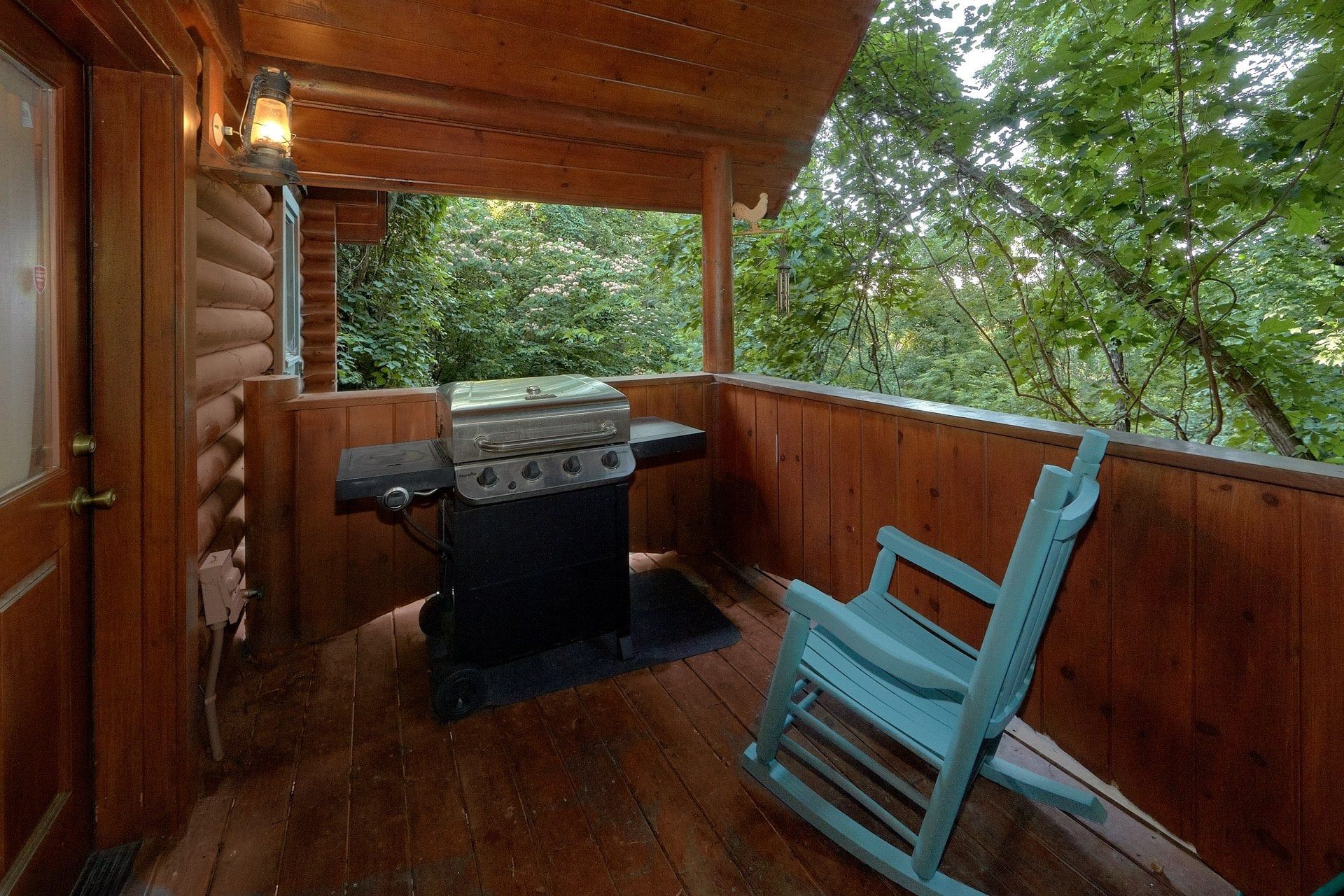A wooden deck with a barbecue grill and a blue chair.