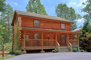 A two-story log cabin with a porch and a small front yard. - Moonshine Inn | Hot Tub, Game Room, Gatlinburg, Resort Pool, Fireplace + Free Attraction Tickets (Gatlinburg)