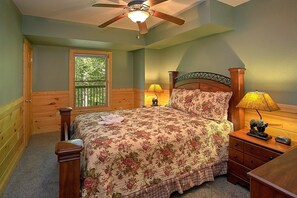 A bedroom with a bed, wooden headboard, two bedside lamps, a nightstand, a dresser, and a ceiling fan. - Moonshine Inn | Hot Tub, Game Room, Gatlinburg, Resort Pool, Fireplace + Free Attraction Tickets (Gatlinburg)